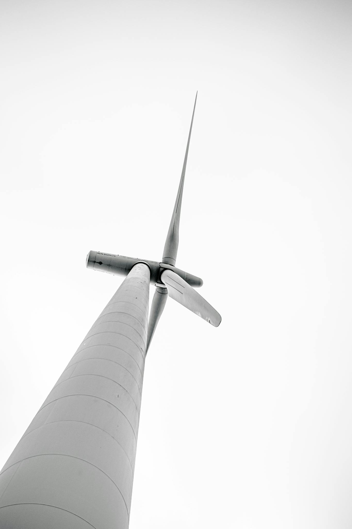 Monochrome photo of a wind turbine viewed from below, emphasizing renewable energy.